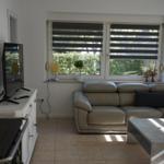 Living room with sofa, coffee table, and windows with blinds.