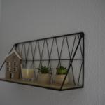 Wall shelf with small plants, candle, and house model on the wall
