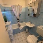 Badezimmer mit Badewanne, Waschbecken und Toilette. Blaue Fliesen und weißer Boden.