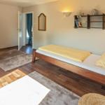 Ein Schlafzimmer mit Holzboden, Bett und Regal an der Wand.