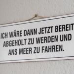 Schild an Wand: Ich wäre dann jetzt bereit, abgeholt zu werden und ans Meer zu fahren.