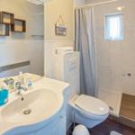 Badezimmer mit Dusche, Toilette und Waschbecken mit Spiegel.