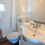 Badezimmer mit Dusche, Toilette und Waschbecken mit Spiegel.
