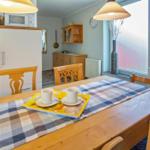 Esszimmer mit Holztisch, Stühlen und Küchenbereich im Hintergrund.