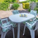Terrasse mit weißem Tisch und vier Stühlen mit Kissen.