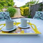 Garten-Tisch mit zwei Tassen auf einem gelben Tablett.