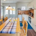 Essbereich mit Holztisch und Stühlen, Küche mit Arbeitsplatte und Geräten.