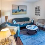 Wohnzimmer mit Sofa, Sessel und Tisch auf blauem Teppich