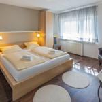 Schlafzimmer mit Doppelbett, Holzmöbeln und Fenster mit Vorhängen.