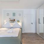 Schlafzimmer mit Bett, Kleiderschrank und Wandbildern.