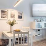 Essbereich mit Tisch, Stühlen und Fernseher an der Wand.