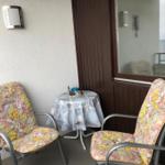 Terrasse mit zwei Stühlen und Tisch. An der Wand hängt ein Thermometer.