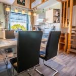 Küche mit Essbereich, Holztreppe und Fenster mit Blick nach draußen.