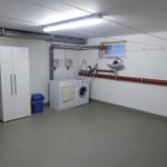 Waschraum mit Waschmaschine, Trockner und Spülbecken an der Wand.