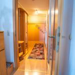 Flur mit Holzboden, Teppich und Schrank. Blumenvase auf Möbel.