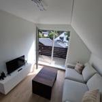 Wohnzimmer mit Sofa, TV und Balkonansicht. Holzboden und modernes Design.