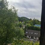 Blick von oben auf eine grüne Landschaft mit Häusern und einem Hügel.