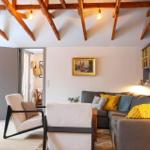 Living room with wooden beam ceiling, sofa and armchairs. Shelving with toys and picture on wall.