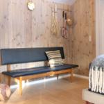 A room with wooden walls, bench, pillow, badminton rackets, and pillow on the bed.