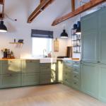 Kitchen with green cabinets, wooden beams, and a window above the sink.