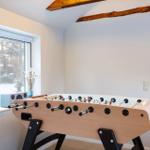 Foosball table in room with wooden beams and snowy window view.