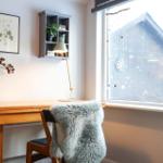Desk with chair and fur throw by large window with candles and decor.