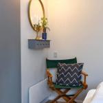 A bedroom with chair, mirror, and wardrobe against the wall.