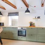 Kitchen with green cabinets, wooden countertops, and built-in oven.