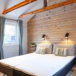 Bedroom with wooden wall, bed, window and chairs.