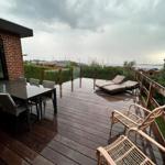 Deck with table, chairs, and loungers. View of water and boats.