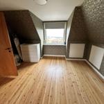 Room with wooden floor, patterned wallpaper, and window with view.