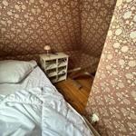 Bedroom with bed, nightstand, and floral wallpaper on the walls.