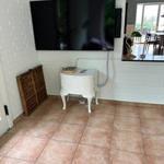 Living area with TV on white brick wall, white side table, and terrace door.