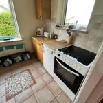 Kitchen with stove, fridge, and windows. Tile floor and mosaic mat.