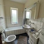Bathroom with bathtub, showerhead, sink, and mirrored cabinet.
