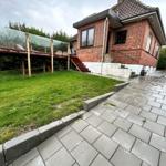 Red brick house with terrace and lawn. Paved path leads to the entrance.