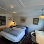 A bedroom with bed, table and window. Wall art and ceiling light are visible.