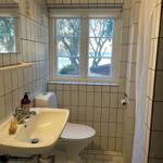 Bathroom with toilet, sink, and window with sea view.
