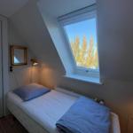 A bedroom with skylight, bed, radiator, and wall mirror.
