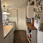 Kitchen with white cabinets, wooden countertop, and tiled floor. Dishware and kitchen utensils are visible.