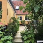 Stone path leads to a yellow house with red roof and windows.