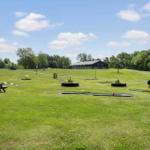 Grünes Feld mit Minigolf, Picknicktisch und Spielplatz. Im Hintergrund ein dunkles Gebäude.