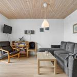 Wohnzimmer mit Sofa, Couchtisch und Fernseher an der Wand.
