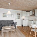 Wohnbereich mit Sofa, Esstisch und Küche unter Holzdecke.