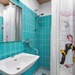 Badezimmer mit Dusche, Waschbecken und Spiegel. Wandfliesen sind türkisfarben.