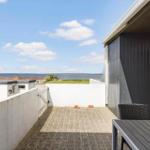 Terrasse mit Tisch und Stühlen, Blick auf Meer und Grünflächen.