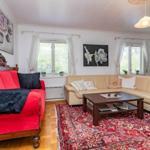 Wohnzimmer mit rotem Sofa, beigem Sofa und orientalischem Teppich.