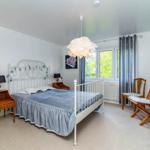 Schlafzimmer mit Bett, Schreibtisch, Fernseher und Fenster mit Blick auf Grün.