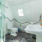 Badezimmer mit Dusche, Toilette und Waschbecken. Wand mit Mosaikverzierung.