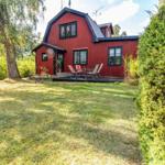 Rotes Holzhaus mit Terrasse und Garten. Möblierte Außenterrasse mit Sitzgelegenheiten.